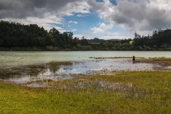 Göl Lagoa das Furnas Sao Miguel Island, Azor Adaları, Portekiz. Taze bitki örtüsü sahile astar. Mavi gökyüzü yoğun bulutlar ile.