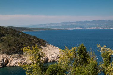 Adriyatik Denizi'nin mavi sularına. Defne her iki kesiminde ağaçta. Dağlar içinde belgili tanımlık geçmiş. Bulutlu bahar gökyüzü. Şehir Vrbnik, görünümden Island Krk, Hırvatistan.