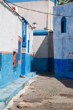 Beyaz ve parlak mavi birlikte hafif beyaz bahar bulutlar ile mavi bir gökyüzü ile eşleşen, boyalı geleneksel mimarisi ile şehrin dar sokak. Kasbah de Oudaias, Rabat, Morocco.