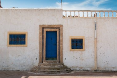 Sokak parlak mavi kapı ve pencere ızgaralar ve cephe beyaz renk bir ev ile. Yuvarlak merdiven. Çatıda Teras. Mavi gökyüzü ile beyaz bulutlar. Sokakta Kasbah de Oudaias, Rabat, Morocco.