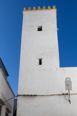Beyaz bir kule ve süslü sarı kenar ile üst bina. Parlak mavi gökyüzü. Sokak Rabat, Morocco.