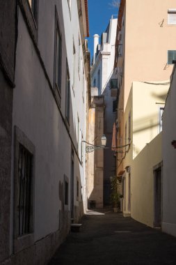 Dar sokak eski tarihi merkezi ile. Mavi gökyüzü. Sokakta bir gölge, kısmen aydınlanmış kısmen. Lisbon, Portekiz.