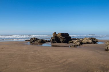 Altın kum ve kayalık plaj Essaouira, Fas Kuzey Atlantik Okyanusu'nun. Küçük dalgalar. Parlak mavi gökyüzü, sonbahar hava.
