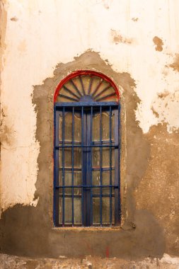 İle eski bir evin duvarına cephe paining kapalı soyulmuş. Kırmızı bir pencere arch, mavi ızgara. Sokak Safi, Fas.