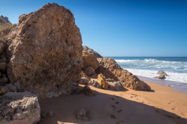 Koyu sarı kum ile temiz plaj buzlu. Atlantik Okyanusu'nun köpüklü dalgalar. Ufuk içinde belgili tanımlık geçmiş. Açık mavi gökyüzü. Lalla Fatna beach (Safi), Fas.