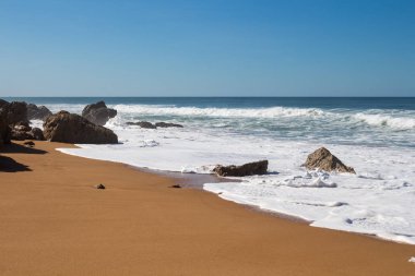 Koyu sarı kum ile temiz plaj buzlu. Atlantik Okyanusu'nun köpüklü dalgalar. Ufuk içinde belgili tanımlık geçmiş. Açık mavi gökyüzü. Lalla Fatna beach (Safi), Fas.