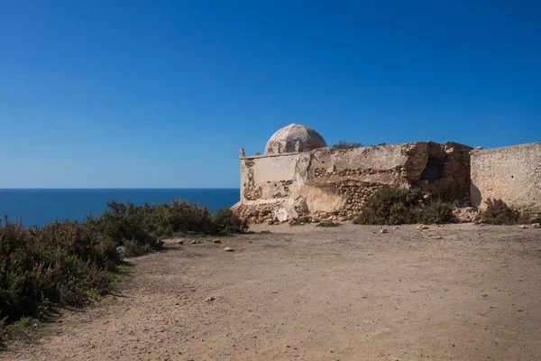 Terk edilmiş mescit / chapel Atlantik Okyanusu kıyı şeridi, bir uçurumun tepesinde. Koyu mavi su okyanusun, parlak mavi gökyüzü. Kuzey Safi, Fas.