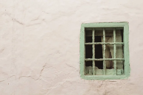 Белая стена и светло-зеленое окно с решеткой — стоковое фото