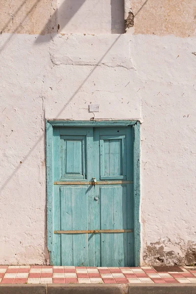 Улица и дом с голубой деревянной дверью — стоковое фото