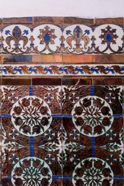 Geleneksel geometrik çiçek güdüsüne sahip duvar kiremitleri, ama daha modern tarzda yüksek parlak metal kaplama sayesinde. Terk edilmiş bir evde duvar. Dar Caid Hacı (aynı zamanda Hacı olarak da bilinir), Safi, Fas 'ın güneyinde..