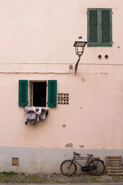 有浅橙色立面的房子 两个装有木制绿色百叶窗的窗户 一个打开了另一个关着 自行车抛锚了洗衣店挂在窗户上Alghero Sardinia 意大利 — 图库照片