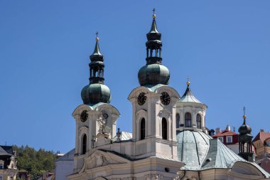 Saatleri ve haçları olan kuleler. Maria Magdalena Kilisesi 'nin diğer tarafında bir kubbe. Parlak mavi yaz gökyüzü. Karlovy Vary (UNESCO), Çek Cumhuriyeti.