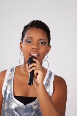 Zenci kadın mikrofonla şarkı söylüyor.