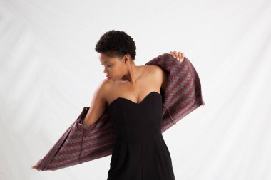 Güzel siyah kadın siyah bir elbise ve ceket içinde dalgın görünüyor.