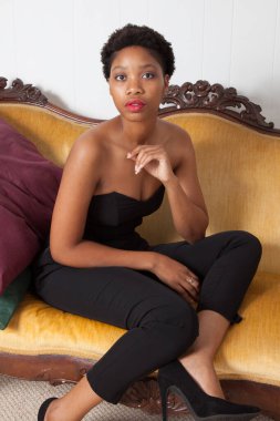 Altın koltukta oturan dalgın siyah kadın.