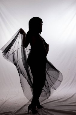 Siluetli bir kadın dalgalı bir bezle dans ediyor.