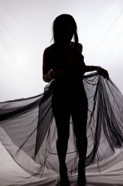 Siluetli bir kadın dalgalı bir bezle dans ediyor.