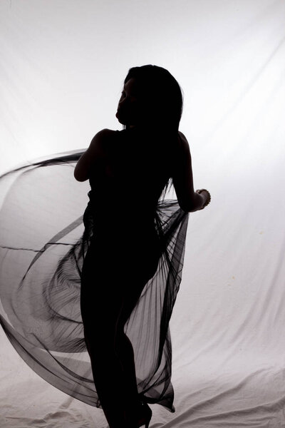 Woman in silhouette dancing with a flowing cloth