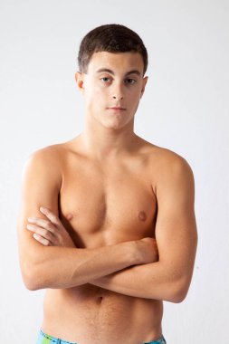 Tişörtsüz ve kollarını kavuşturmuş dalgın bir adam.