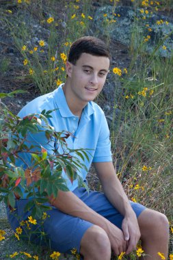 Yakışıklı adam dışarıda oturuyor ve rahatlıyor.