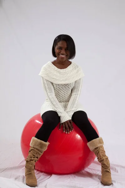 快乐的黑人女人坐在一个红色的运动球上 — 图库照片