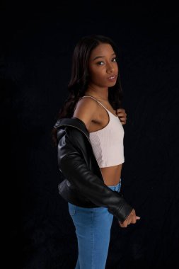 Siyah deri ceketli hoş bir kadın, düşünceli görünüyor.