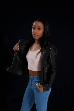 Siyah deri ceketli hoş bir kadın, düşünceli görünüyor.