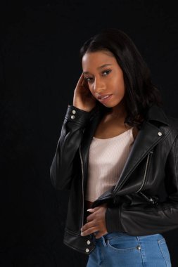 Siyah deri ceketli hoş bir kadın, düşünceli görünüyor.