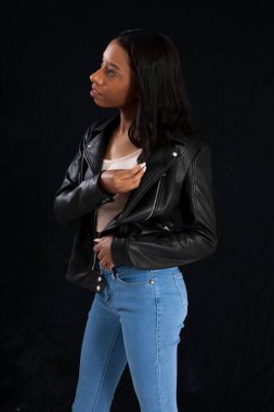 Siyah deri ceketli hoş bir kadın, düşünceli görünüyor.