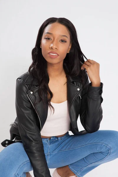 Pensive Black woman squatting in blue jeans