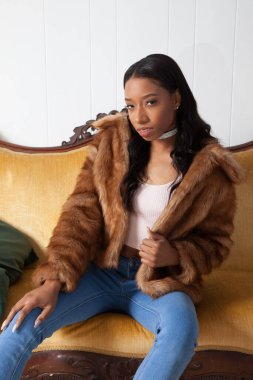 Kürklü güzel kadın düşünceli bir şekilde oturuyor.