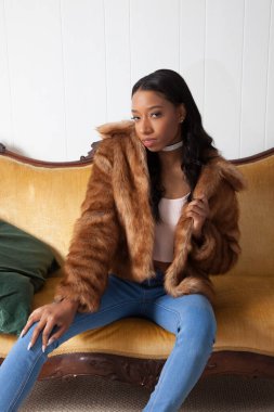 Kürklü güzel kadın düşünceli bir şekilde oturuyor.