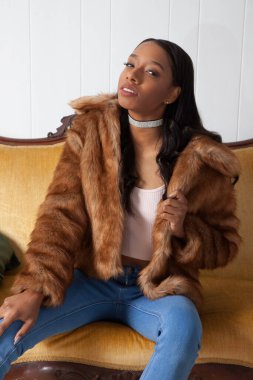 Kürklü güzel kadın düşünceli bir şekilde oturuyor.