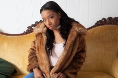 Kürklü güzel kadın düşünceli bir şekilde oturuyor.