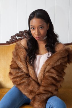 Kürklü güzel kadın düşünceli bir şekilde oturuyor.