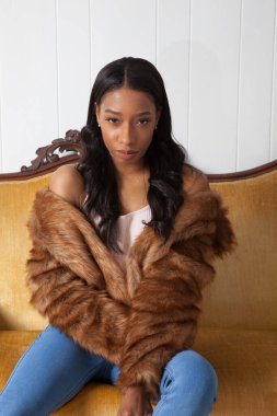 Kürklü güzel kadın düşünceli bir şekilde oturuyor.