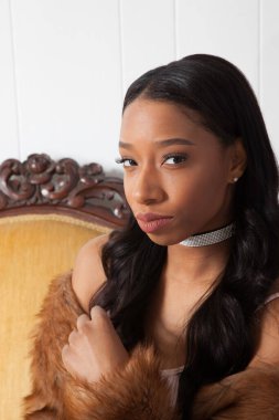 Kanepede oturan dalgın siyah kadın.