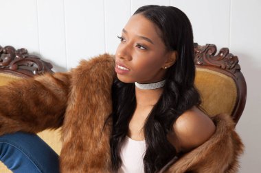 Kanepede oturan dalgın siyah kadın.