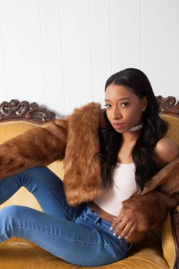 Güzel bir kadın kanepede dinleniyor ve düşünceli görünüyor.