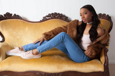 Güzel bir kadın kanepede dinleniyor ve düşünceli görünüyor.