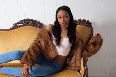 Güzel bir kadın kanepede dinleniyor ve düşünceli görünüyor.