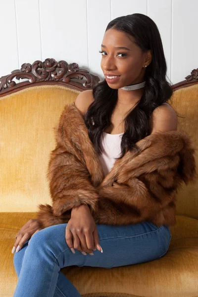 Kürklü güzel bir kadın, hoş bir gülümsemeyle oturuyor.