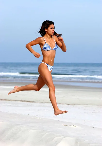 Mid Air Run Exorcise - Bright Blue Flowered print Skimpy swimwear - Hard Body Hard Abs Small Swimsuit Smalls breasts sun drenched free woman in free pose playful beach sand ocean sunlight form sunrise to sunset in Daytona Beach Florida
