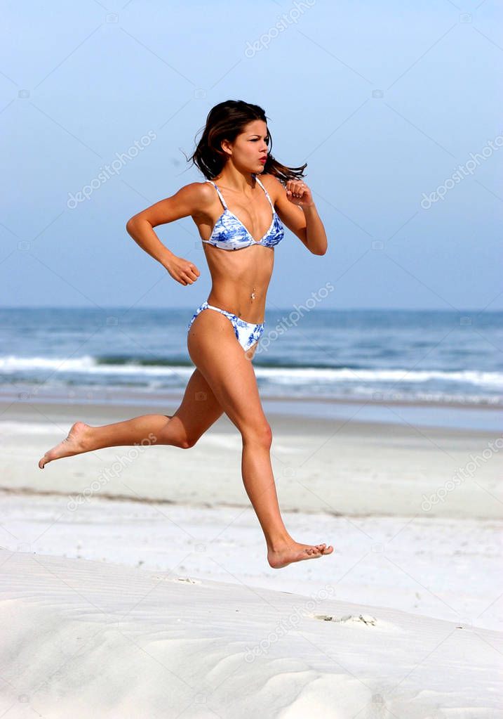 Mid Air Run Exorcise - Bright Blue Flowered print Skimpy swimwear - Hard Body Hard Abs Small Swimsuit Smalls breasts sun drenched free woman in free pose playful beach sand ocean sunlight form sunrise to sunset in Daytona Beach Florida 