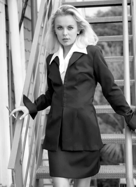 Monochrome portrait of European lady in Black business suit - white collard shirt - on staircase headed for interview for a job - employment opportunity accountant legal aid vice president business owner - female executive