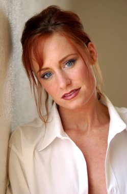 Mavi gözlü yumuşak ifade - düz saçları Kızıl - siyah eyeliner ve pembe ruj ve hafif hafif Erik dudak parlatıcısı ile doğrudan kameraya bakarak çarpıcı beyaz kolalı iş gömlek güzel genç kadın