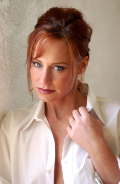 Yumuşak ifade - düz saçları Kızıl - siyah eyeliner ve pembe rujla doğrudan kameraya bakarak ve ışık Erik dudak parlatıcısı - gri arka plan ve kopya alanı bastırılmış çarpıcı mavi gözlü beyaz kolalı iş gömlek güzel genç kadın