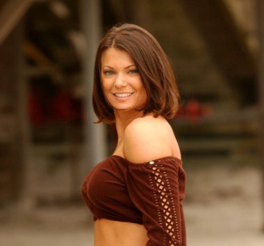 Etkin görünüm - doğrudan kameraya arıyorum - derin, karanlık çikolata kahverengi keçe uzun kollu tüp üst gömlek büyük göğüsler - mavi jeans - profesyonel moda kapsayan model - Tan sesi açık cilt çıplak silah - playa otel plaj kum arka plan etkileyici abs