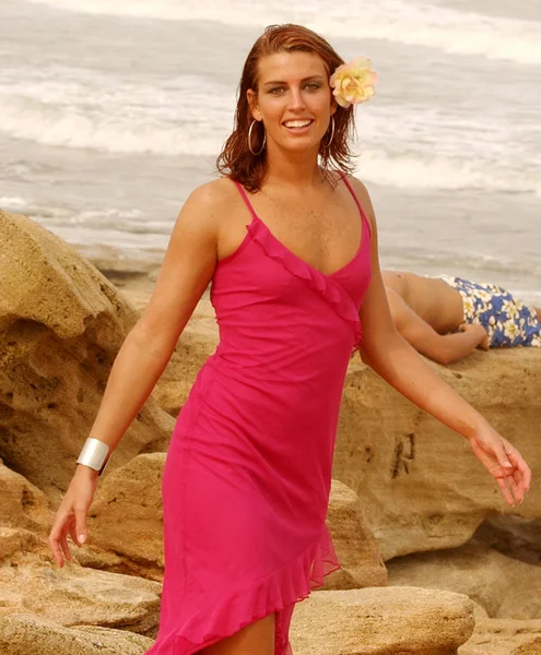 モデルの髪のビーチの海辺の黄色の花を歩いて座って薄いモデルに明るい色の長いドレス — ストック写真
