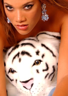 Muhteşem genç oynak Bayan bir beyaz kaplan oyuncak çıplak ayı - mavi saten çarşaflar arka plan - mavi gözleriyle oynuyor